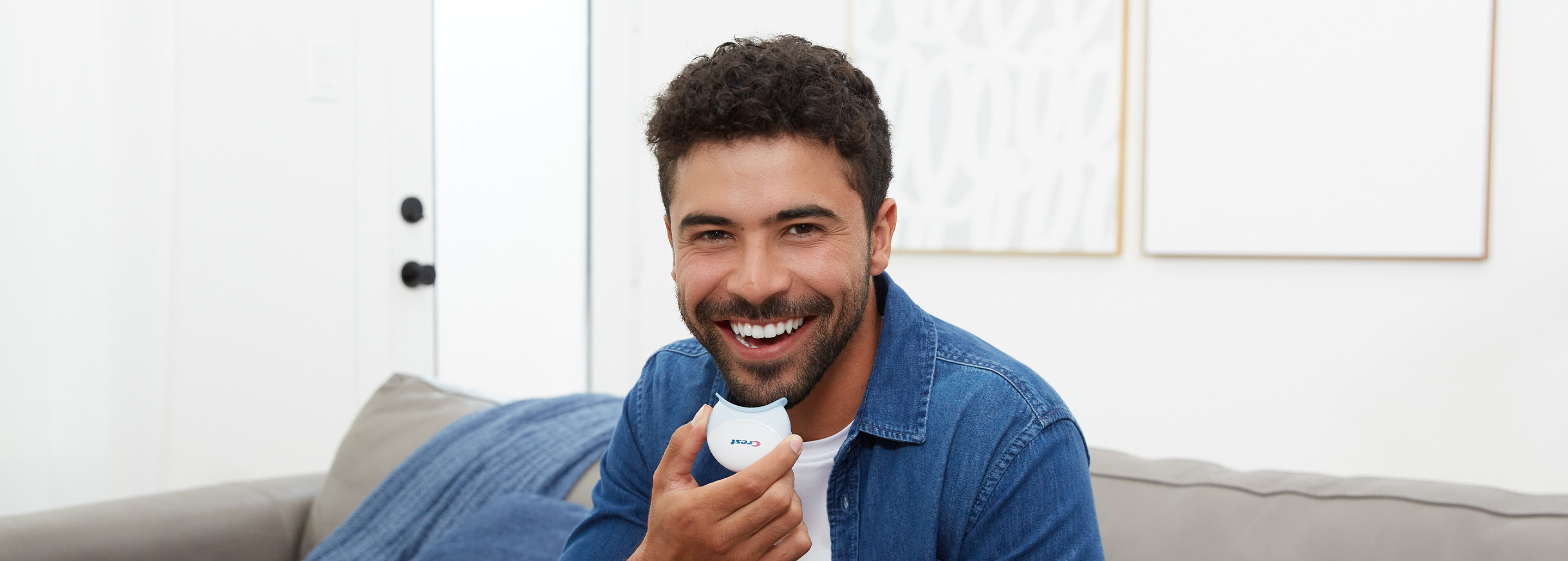 Curly-haired brunette man smiles ahead as he holds a Crest LED Accelerator Light.