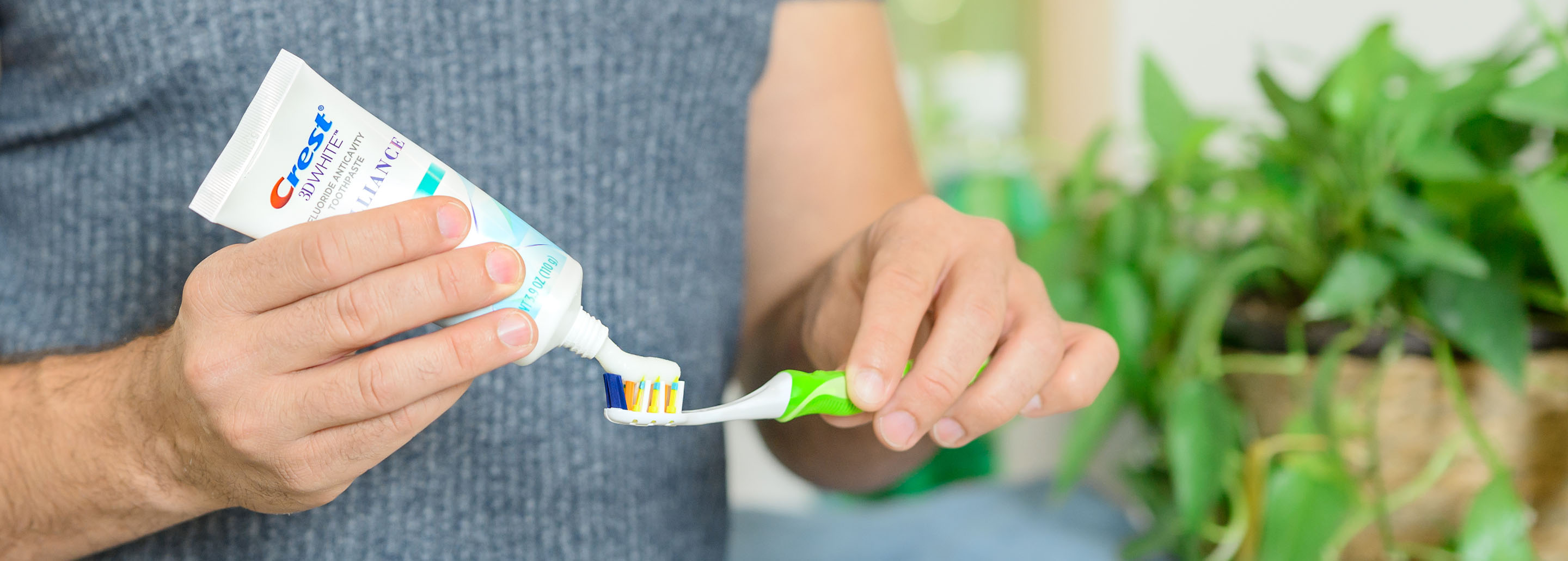 Man squeezes Crest 3DWhite Brilliance Toothpaste onto his toothbrush.